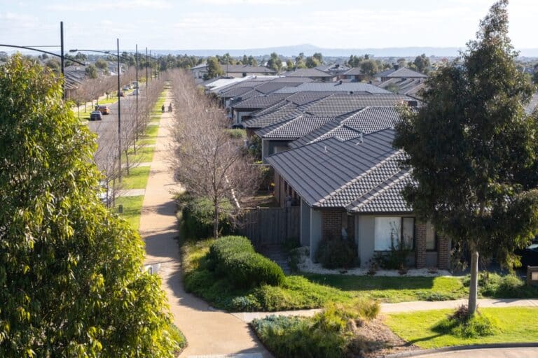 Suburban neighborhood with rows of houses, a paved pathway, and landscaping.