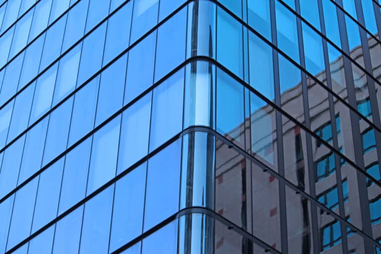 The image shows the corner of a modern glass building with reflective blue windows.