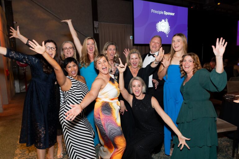 A group of women in elegant formal attire smiling and posing together for a photograph at the 2025 QLD People in Property Awards