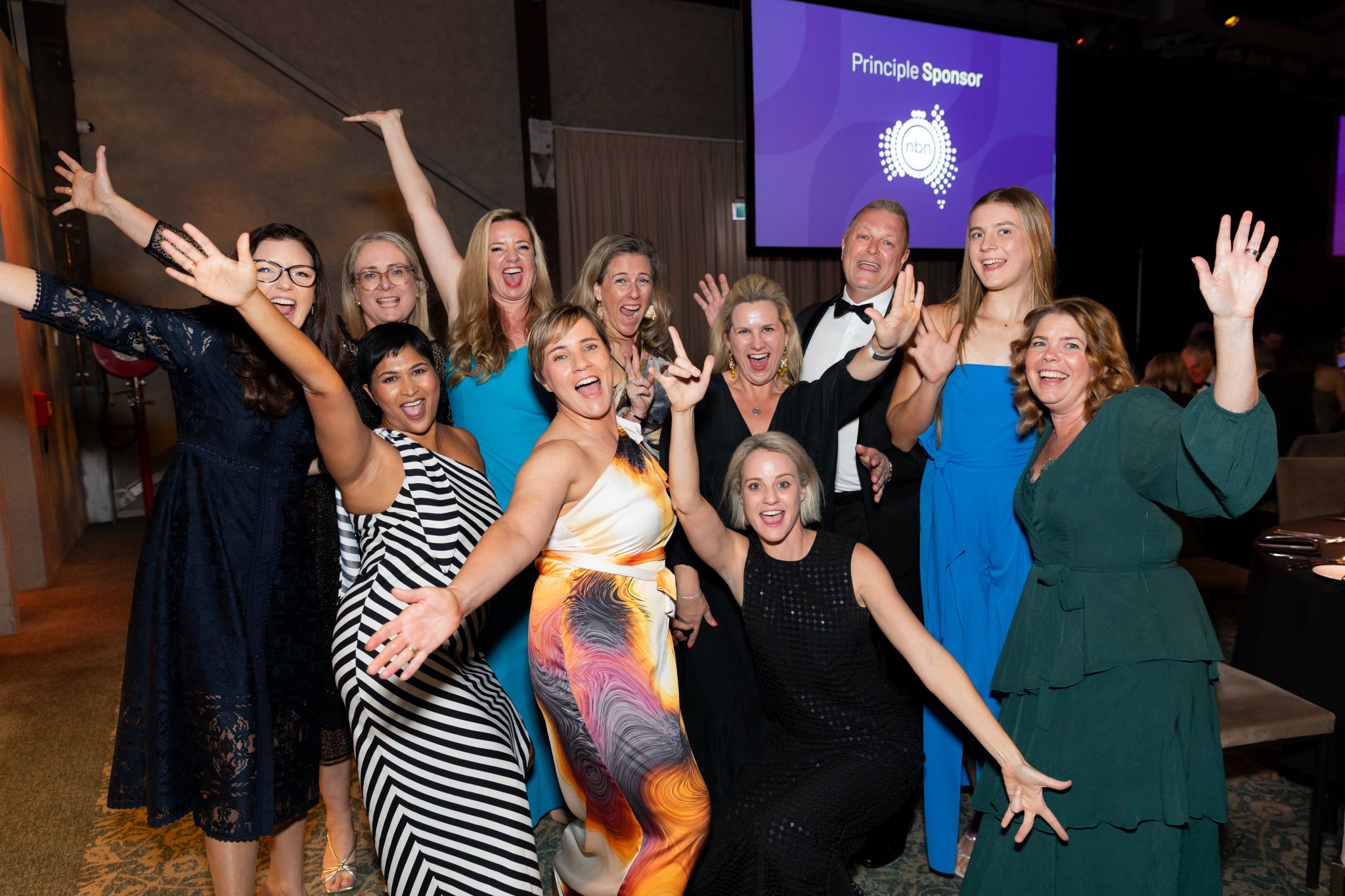 A group of women in elegant formal attire smiling and posing together for a photograph at the 2025 QLD People in Property Awards