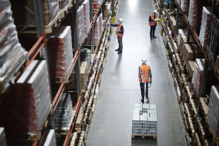 A warehouse worker moves between rows of boxes, overseeing the inventory in a busy storage environment.